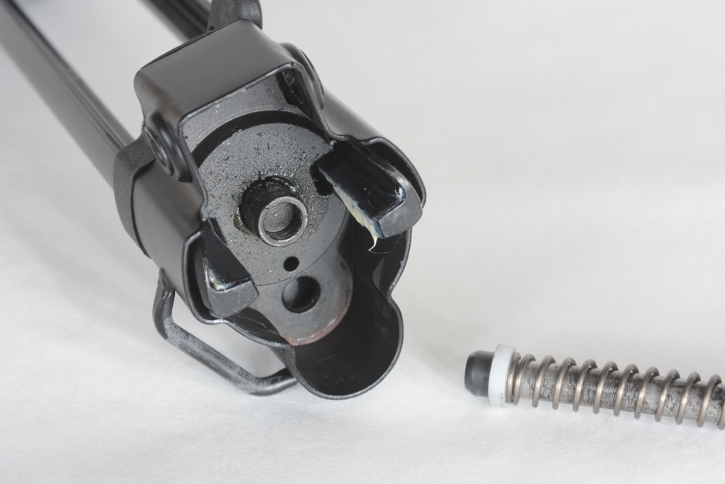 The long end of the recoil system is inserted into the top hole on the endcap (shown upside down in this photo), above the plunger for the recoil buffer.