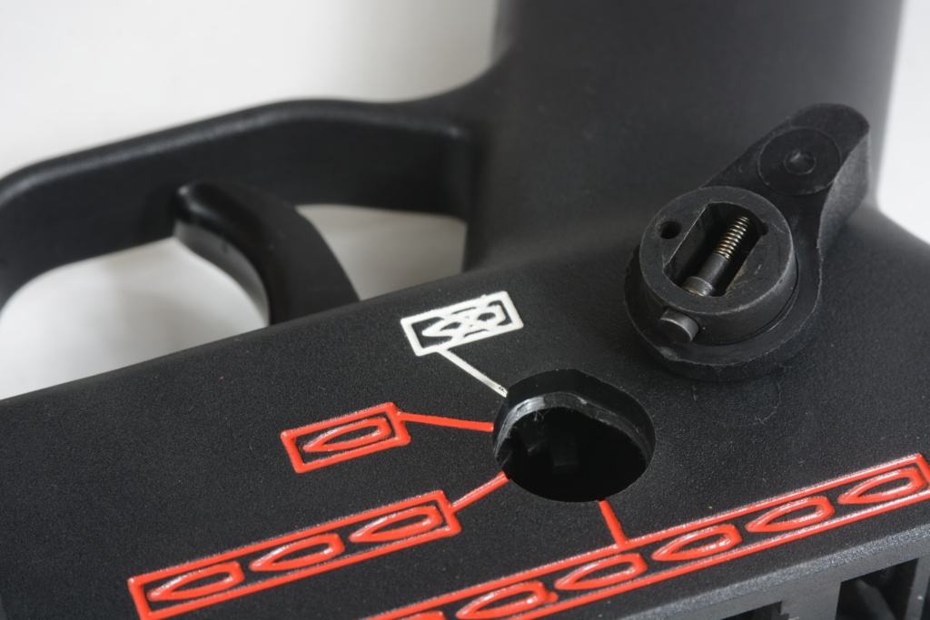 The right-side lever is held in by a spring-loaded plunger. The side of the trigger housing is ovaled at the bottom to allow the lever to be installed.